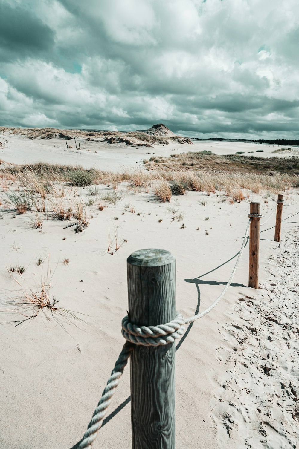 brown wooden fence on white sand under white clouds during daytime