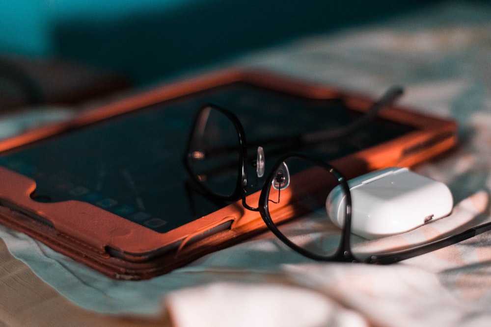 a pair of glasses sitting on top of a tablet