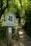 A wooden post with a sign indicates a pathway leading through a lush, green wooded area. The sign reads 'The National Trust' and 'Devil's Dyke' with a small secondary sign indicating access land.