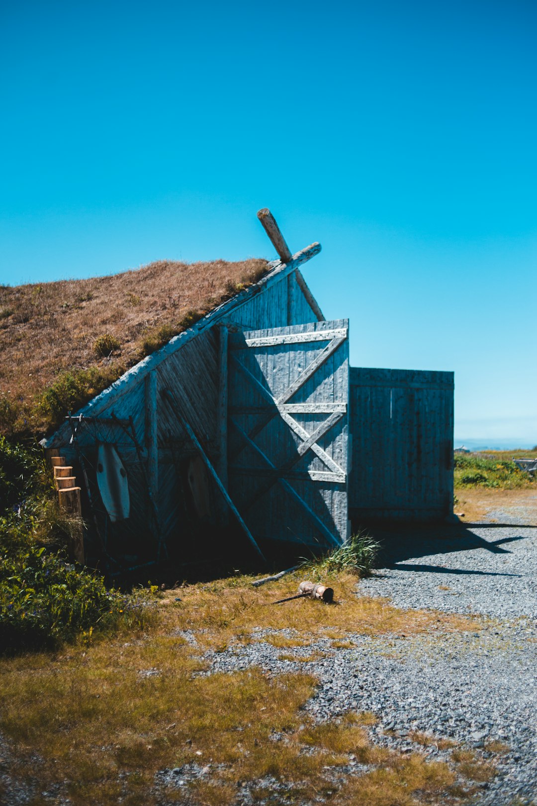 blue wooden shed on brown field during daytime