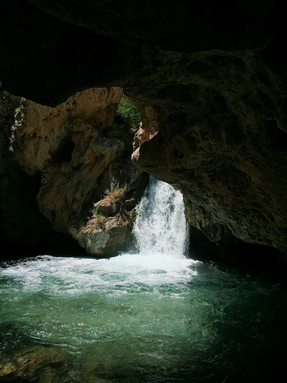 water falls in cave during daytime