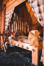 Interior of a rustic cabin featuring a comfortable double bed, wooden furniture, and nature-inspired decorations.