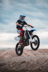 man in black and red motorcycle suit riding on red and white motocross dirt bike
