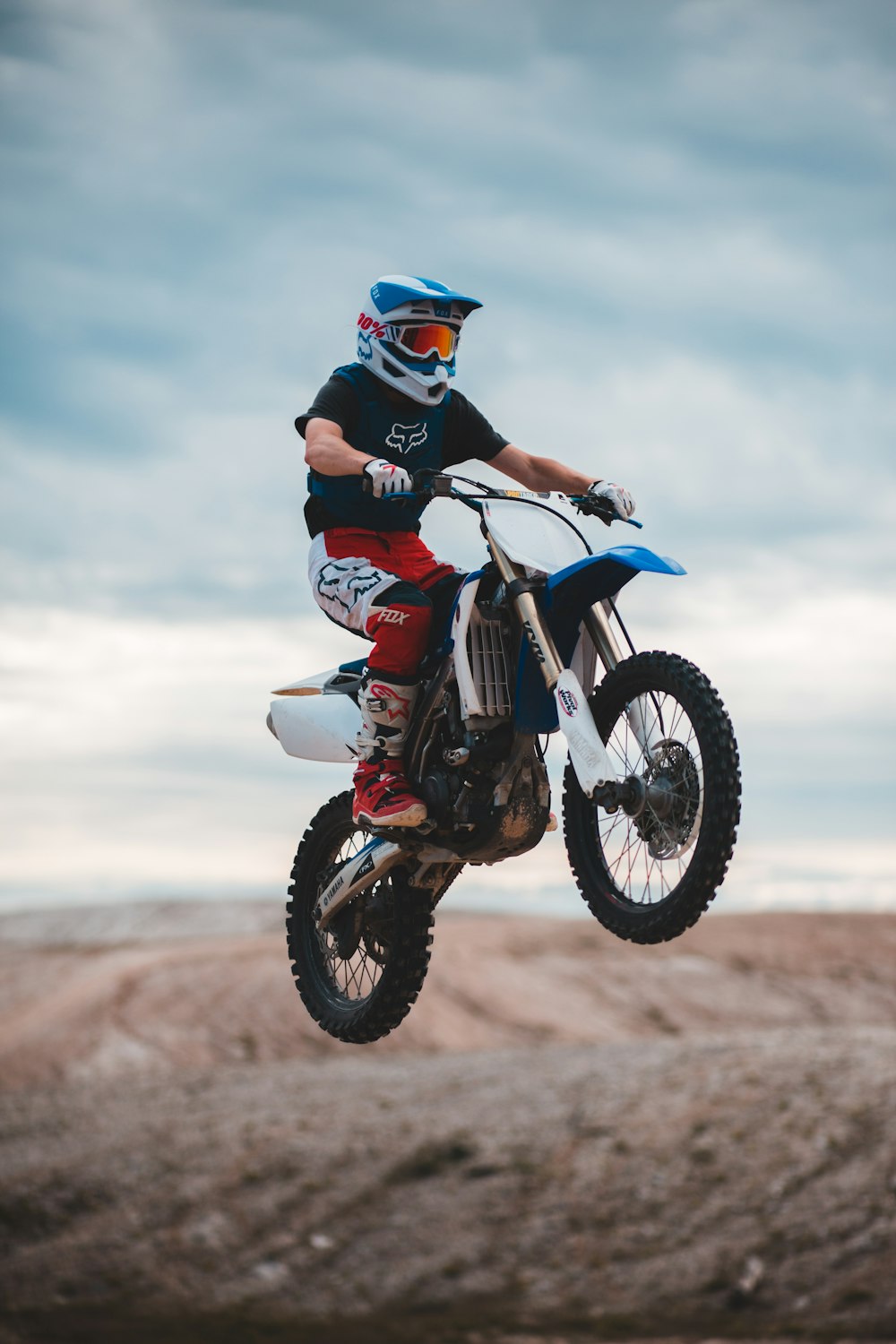 homem em terno de motocicleta preto e vermelho andando em moto de terra de motocross vermelho e branco