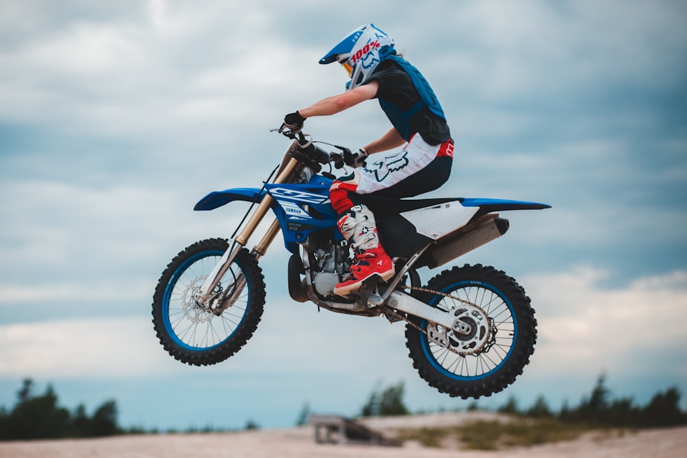 man in black and blue motorcycle suit riding blue and white motocross dirt bike