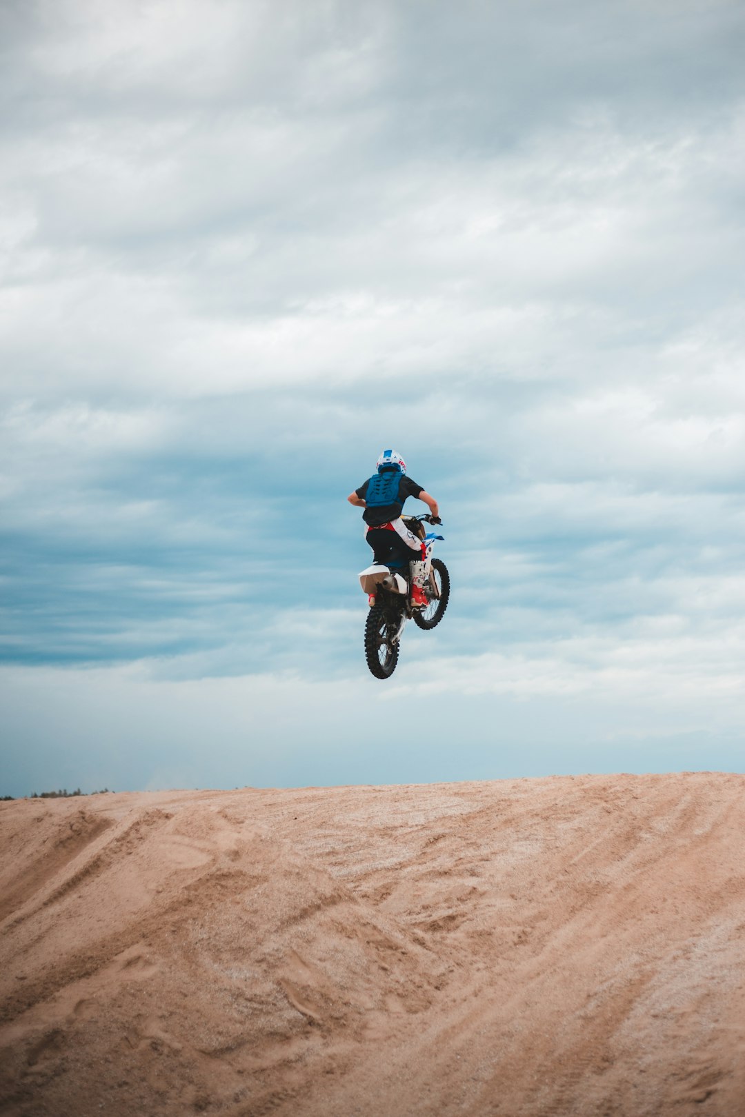 man in black jacket riding on black bmx bike on brown sand under white clouds during