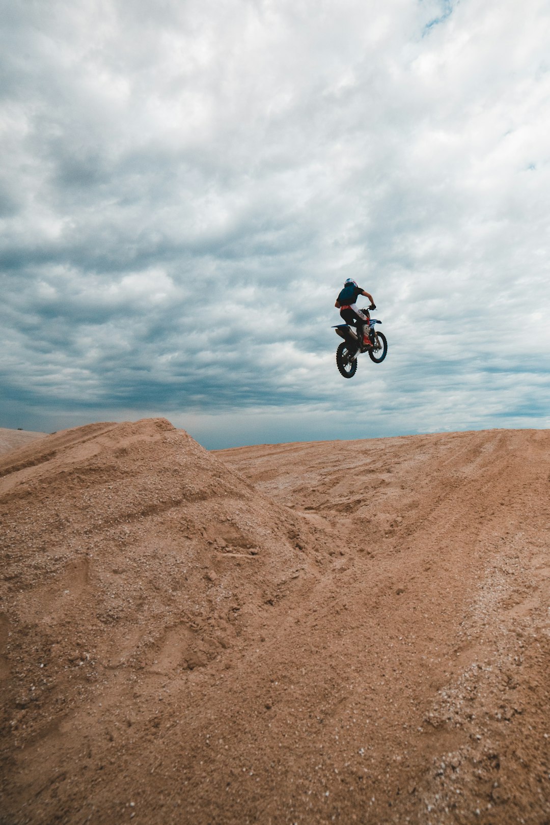 man in black jacket riding on bicycle on brown sand under white clouds during daytime
