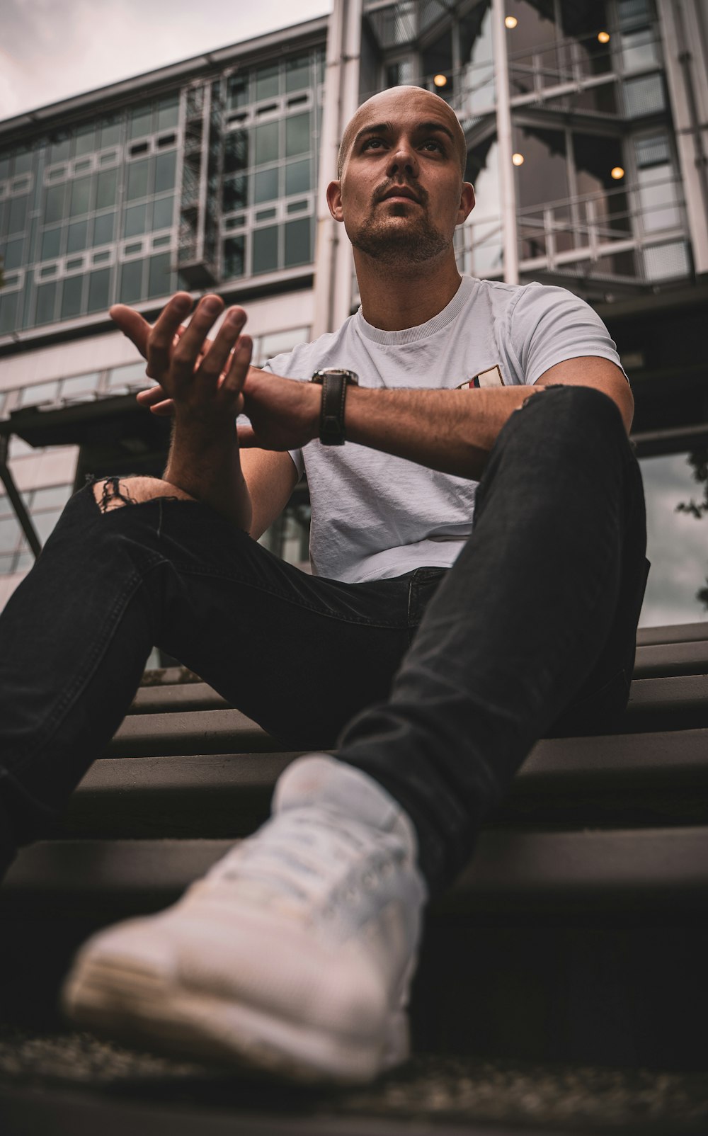 man in white shirt and black denim jeans sitting on black wooden bench