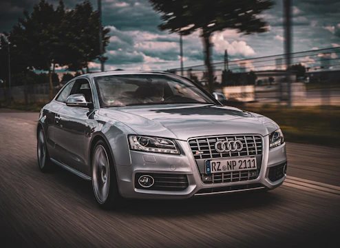 A sleek Audi with a turbo upgrade racing on a winding track under a clear blue sky.