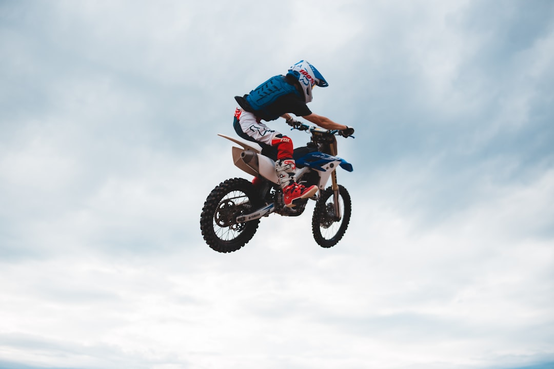 man in blue jacket riding motocross dirt bike