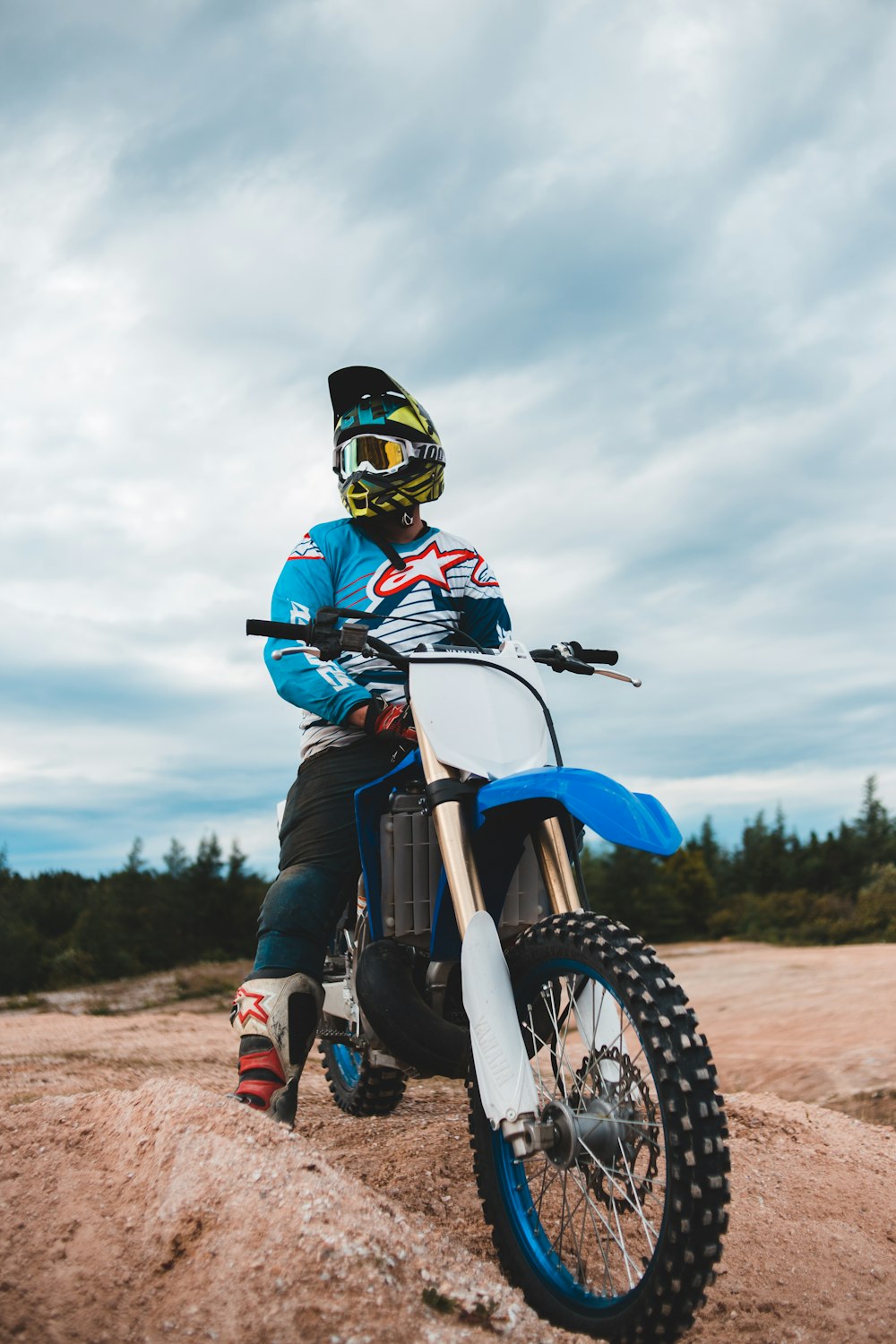 man in blue and red motocross helmet riding blue and white motocross dirt bike
