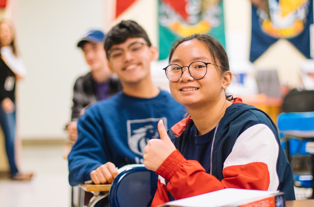 boy in blue and red sweater wearing eyeglasses smiling