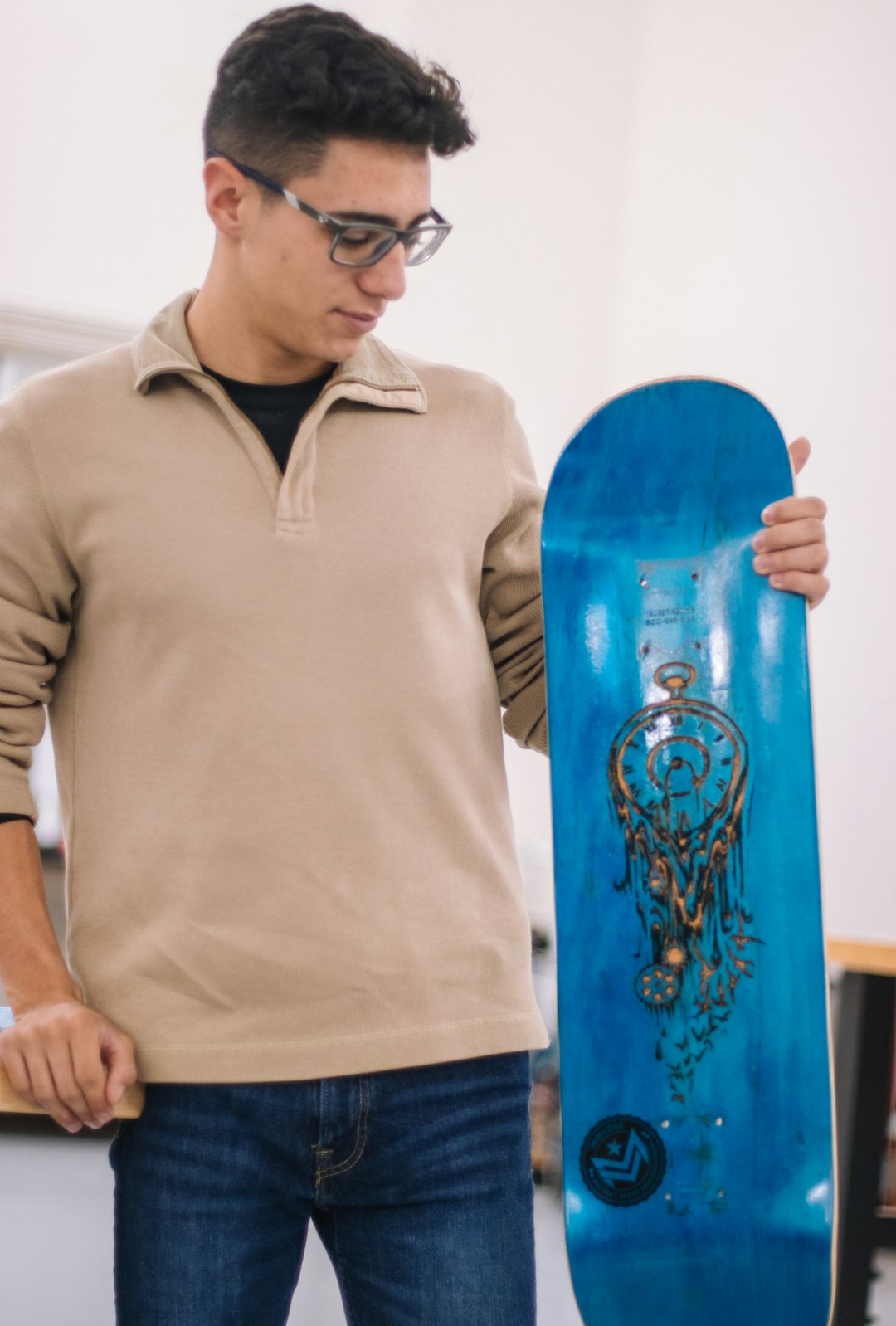 man in gray polo shirt holding blue skateboard