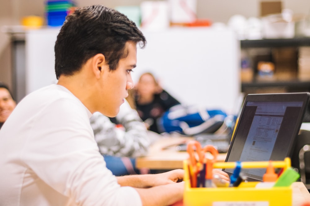 man in white long sleeve shirt using black laptop computer