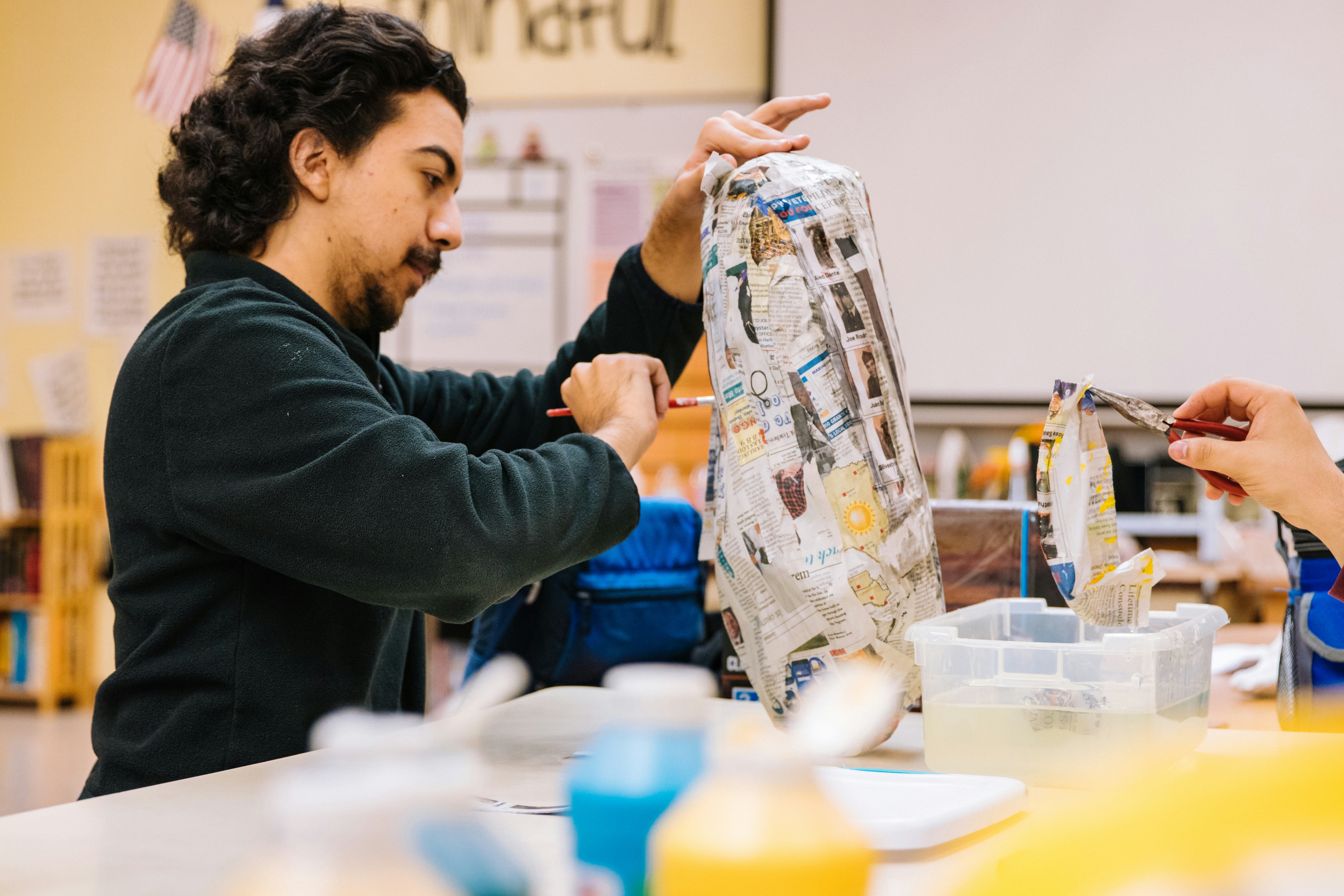 man in black jacket holding clear glass pitcher