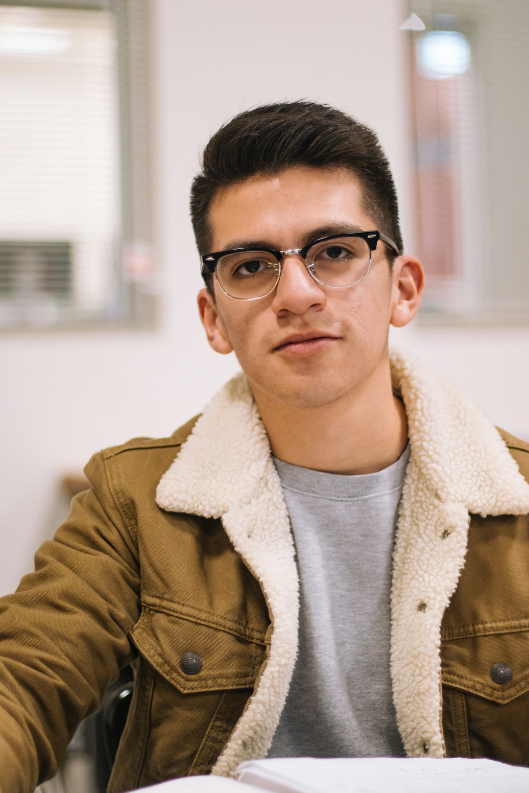 man in brown jacket wearing black framed eyeglasses