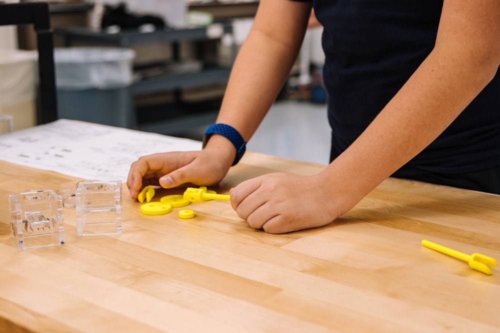 person in blue and white long sleeve shirt holding yellow plastic toy