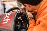 boy in orange jacket using black and red steering wheel