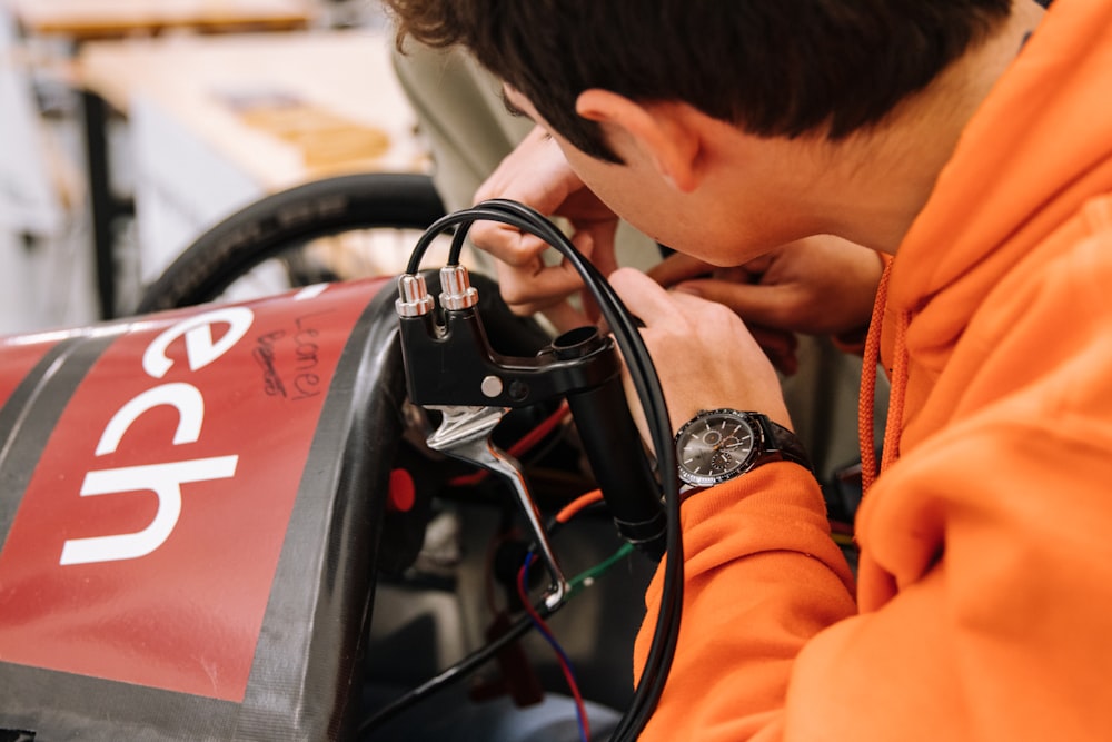 boy in orange jacket using black and red steering wheel