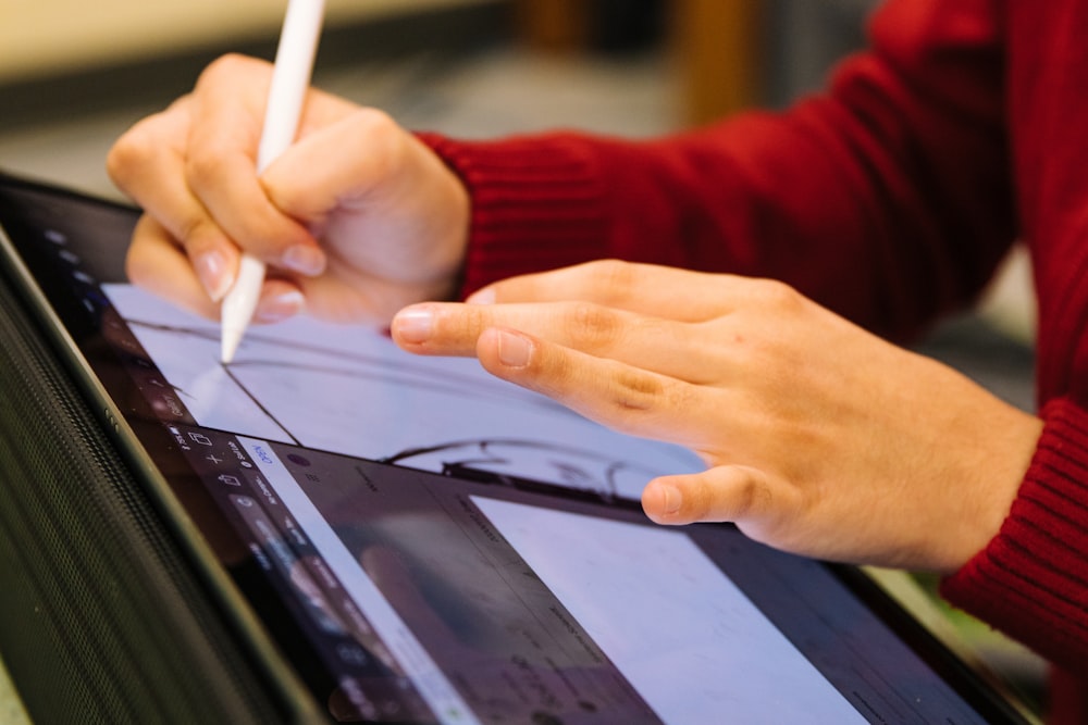 person in red long sleeve shirt holding white pen