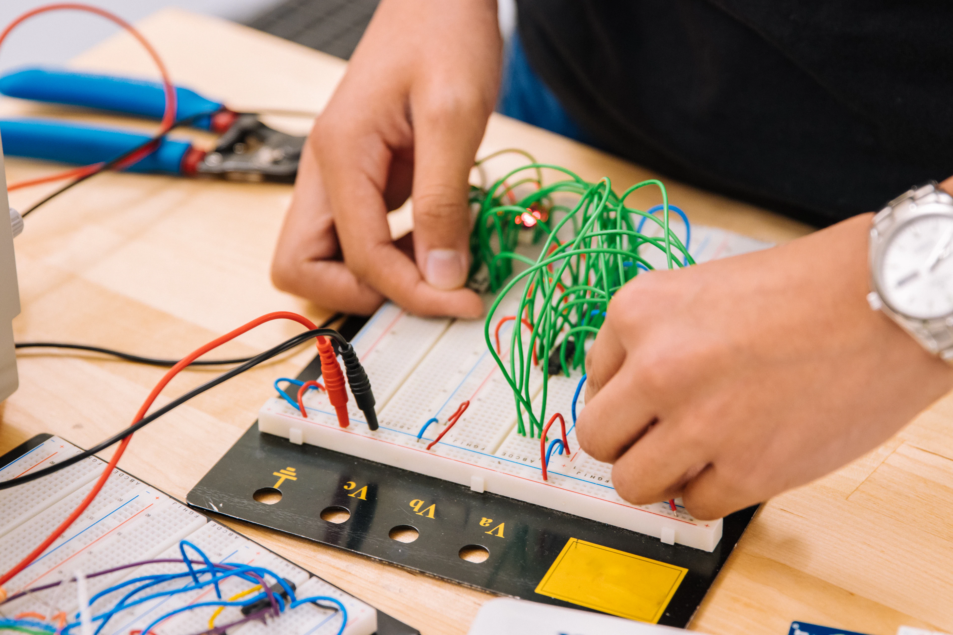 Close-up of hands wiring a robotics circuit board