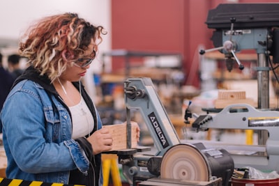 woman in blue denim jacket holding white and black power tool santa's workshop google meet background