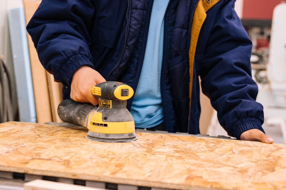 person holding black and yellow cordless hand drill