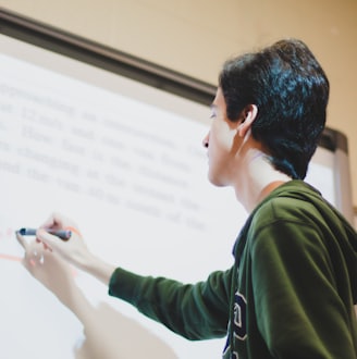 man in green and white long sleeve shirt writing on a white board