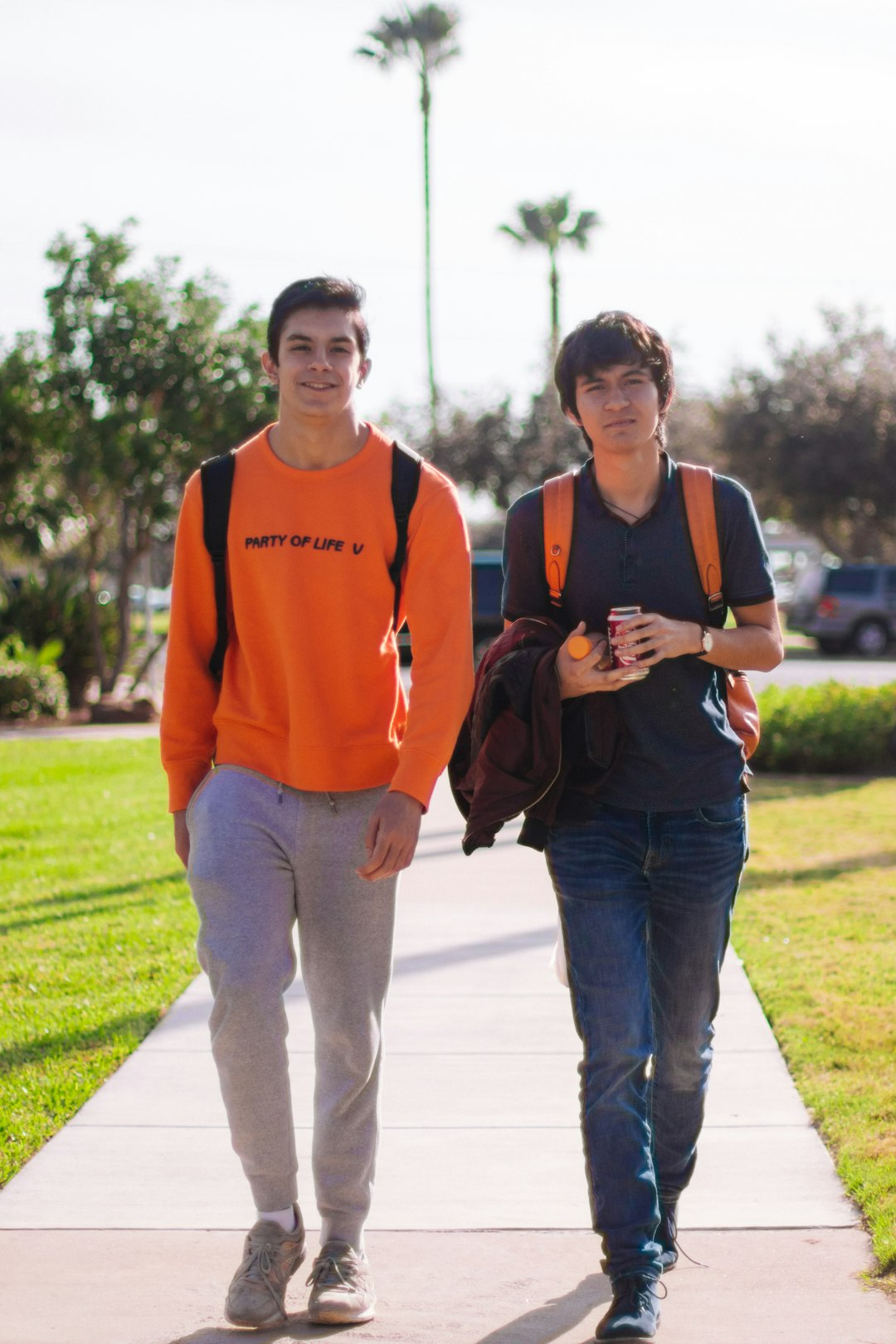 man in orange and black hoodie standing beside woman in orange long sleeve shirt