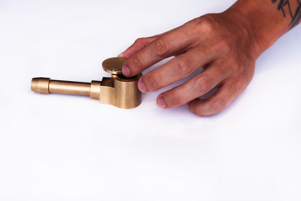 person holding gold and silver steel tube