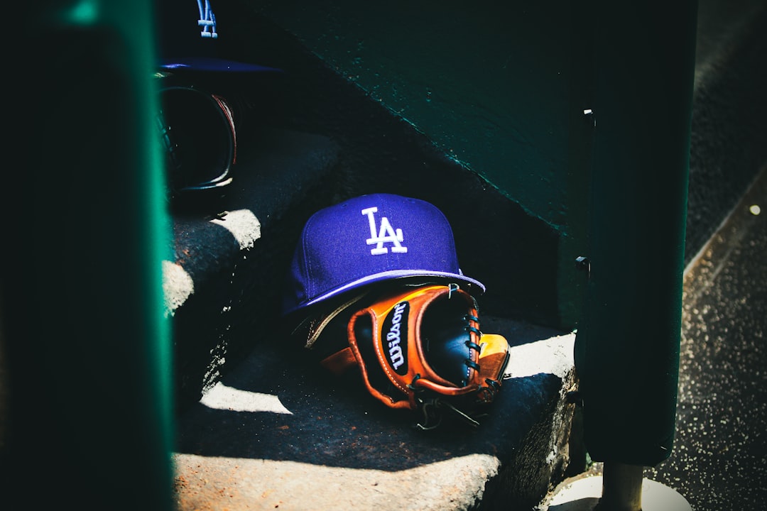 man in blue and orange helmet and goggles - Dodgers hat rests on the dugout steps.if photo is used, please provide the following photo cred:Photo by Desmond A. Hester // @dezhester