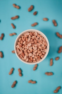 A happy customer holding a bowl of fresh peanuts with a bright kitchen background.