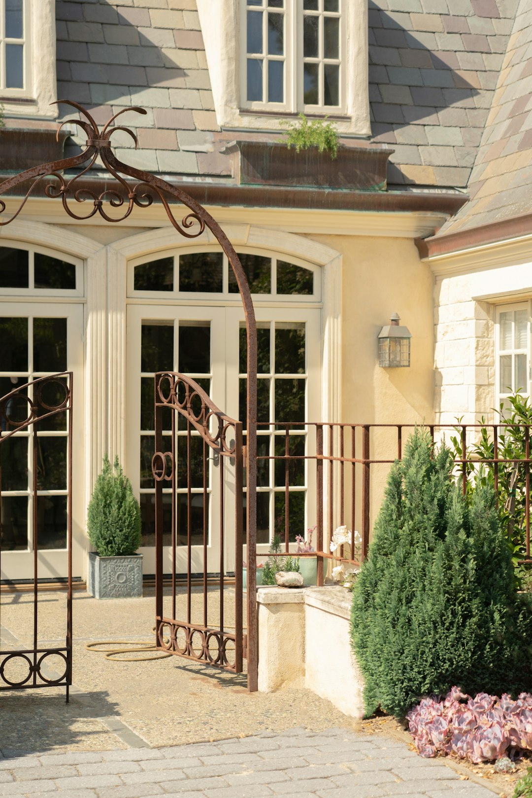 brown metal gate near green plants during daytime