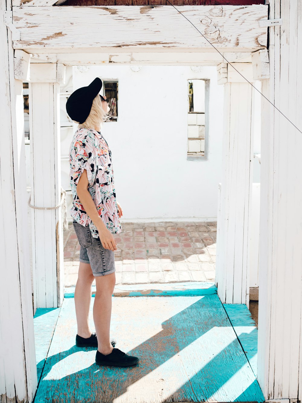 woman in white red and black floral shirt standing on blue and white floor tiles