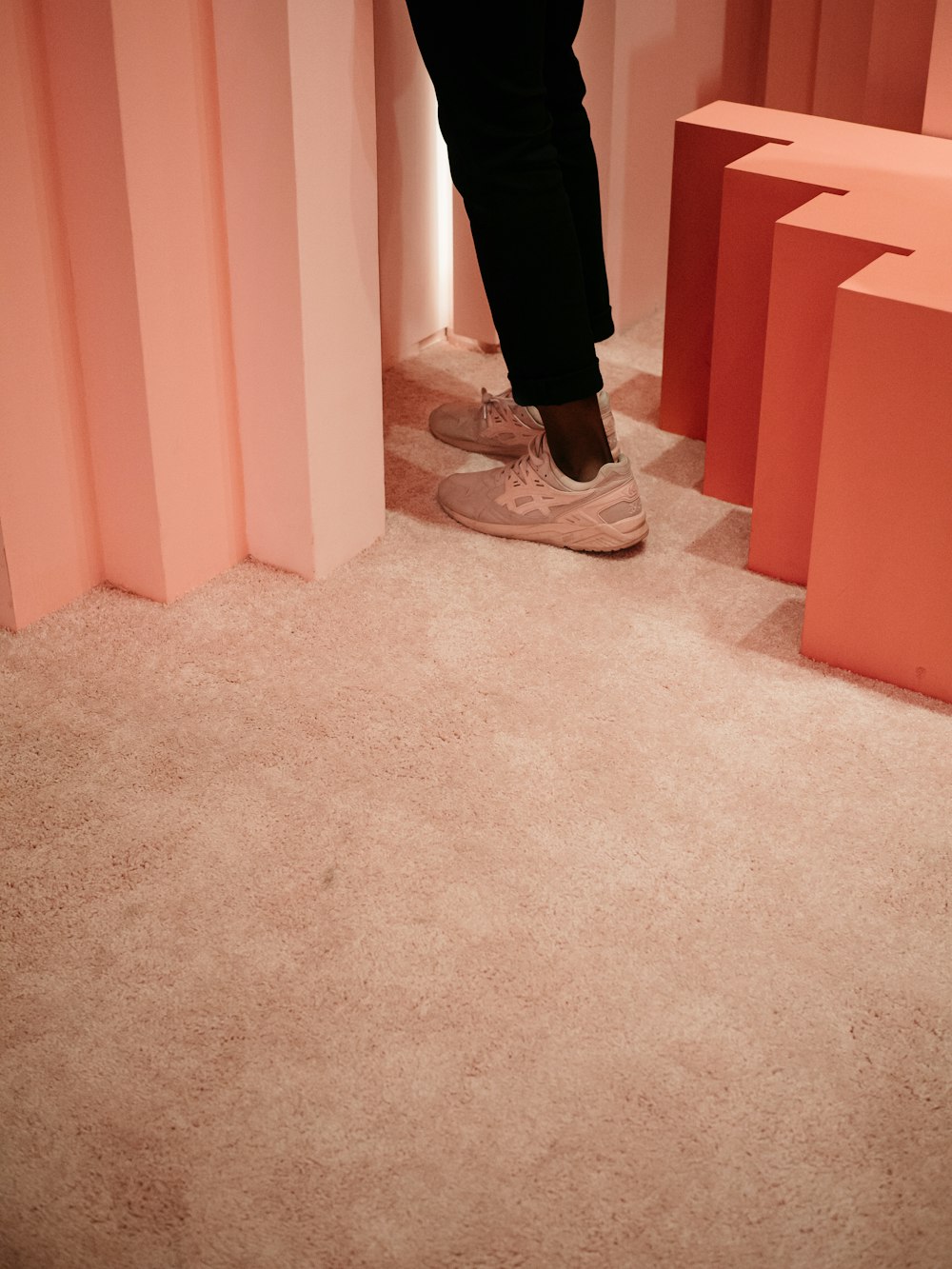 person in black pants and white sneakers standing on brown carpet