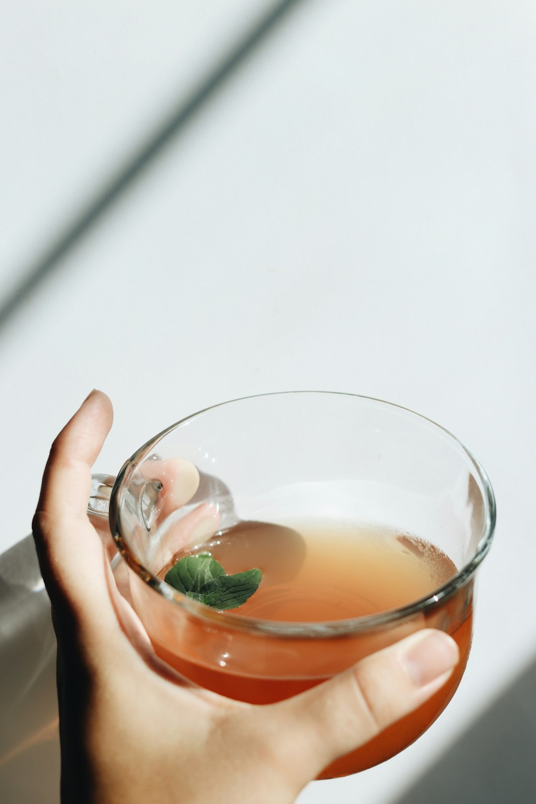 person holding clear drinking glass with dandelion root tea inside