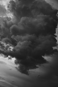 Dark and dense storm clouds loom ominously in the sky, creating a dramatic, looming formation. The scene conveys a sense of intensity and impending weather change with shadows and contrast defining the swirling masses.