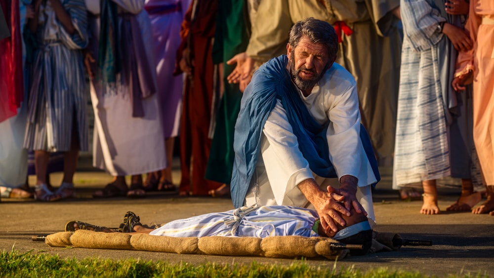 man in white thobe sitting on brown textile