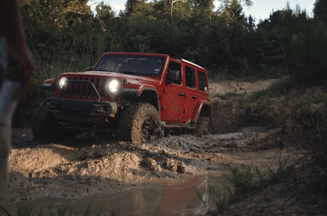 red suv on brown dirt road during daytime riding on off road tyres available at tyrepublic