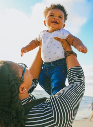 woman in black and white striped long sleeve shirt carrying baby in blue onesie