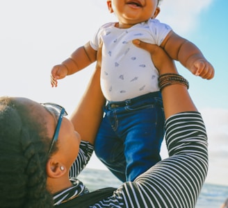 woman in black and white striped long sleeve shirt carrying baby in blue onesie