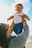 woman in black and white striped long sleeve shirt carrying baby in blue onesie