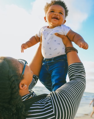 woman in black and white striped long sleeve shirt carrying baby in blue onesie