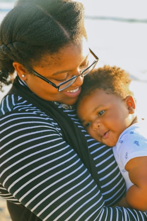 man in black and white striped shirt carrying baby in white and blue onesie
