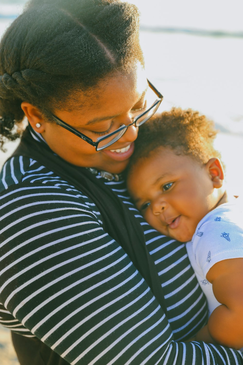 man in black and white striped shirt carrying baby in white and blue onesie