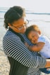 woman in black and white striped shirt carrying baby in white and blue onesie