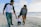 man in black and white striped long sleeve shirt holding baby in white shirt on beach