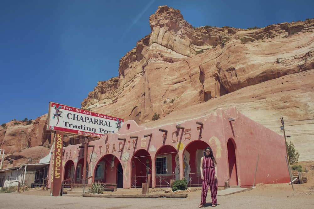 woman in red dress standing near brown rock formation during daytime