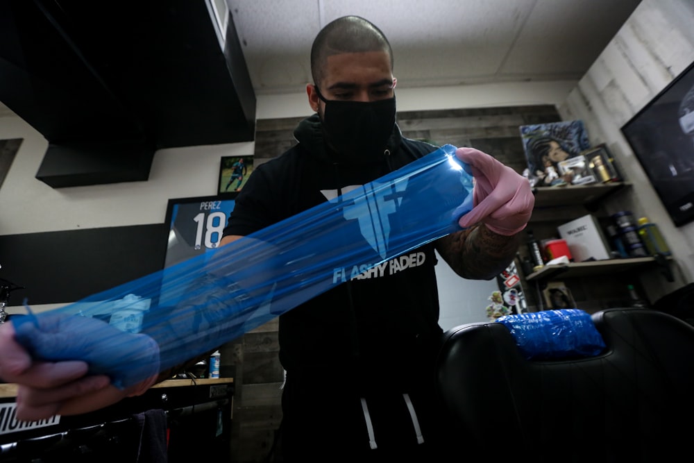 man in black jacket holding blue plastic bottle