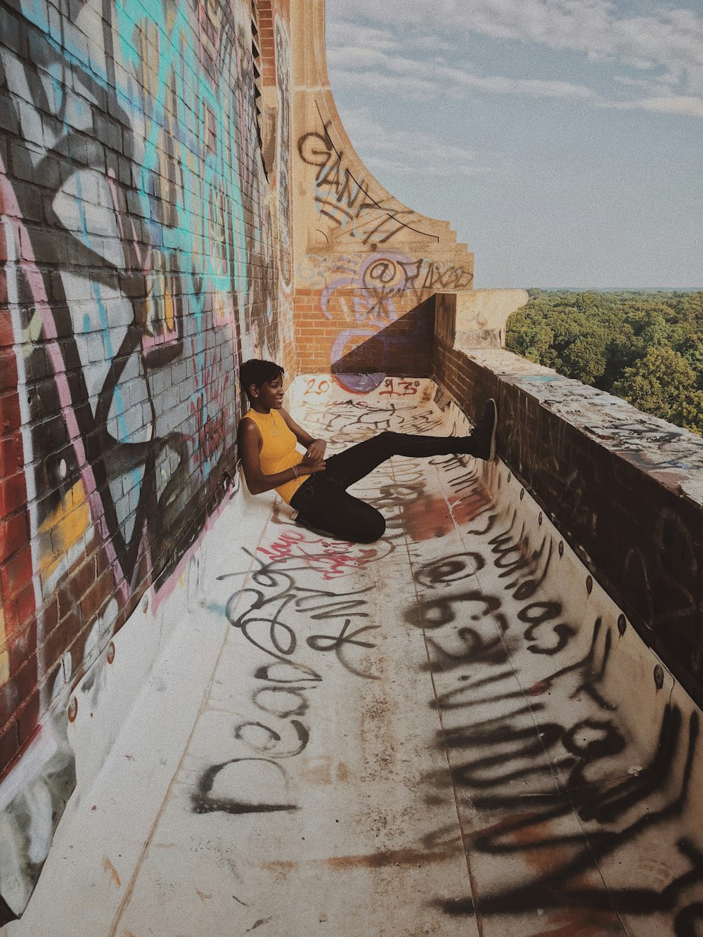 woman in black tank top and black pants sitting on concrete floor during daytime